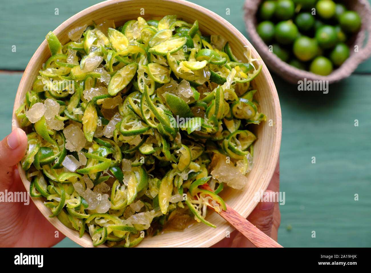 Vista dall'alto di persone tenere in mano una ciotola di kumquat peel fetta tagliata e mescolare con lo zucchero di roccia, questo aspro frutto ricco di vitamina C, sano e rendere detox drink Foto Stock