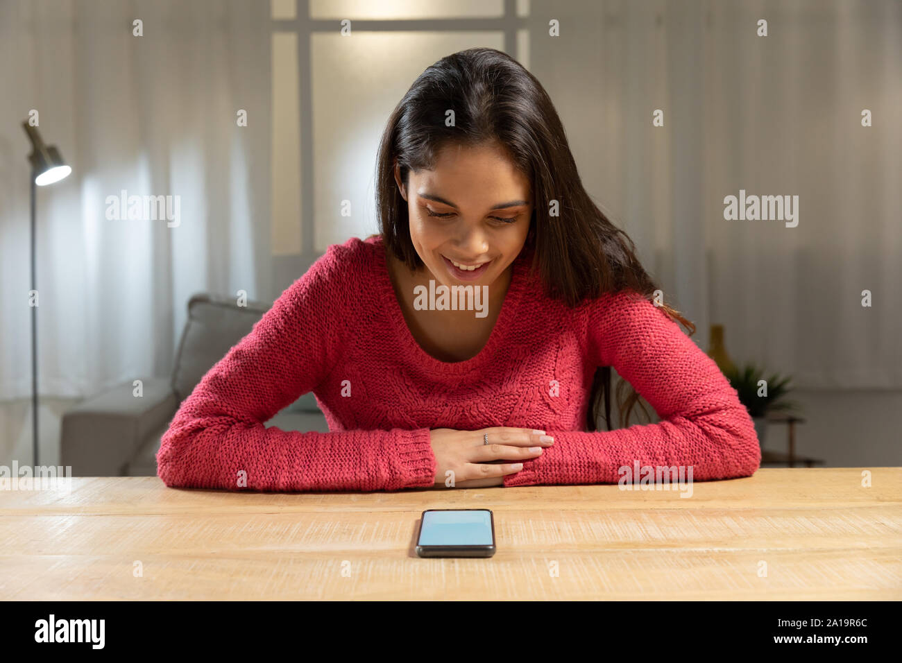 Giovane donna utilizza lo smartphone su un tavolo Foto Stock