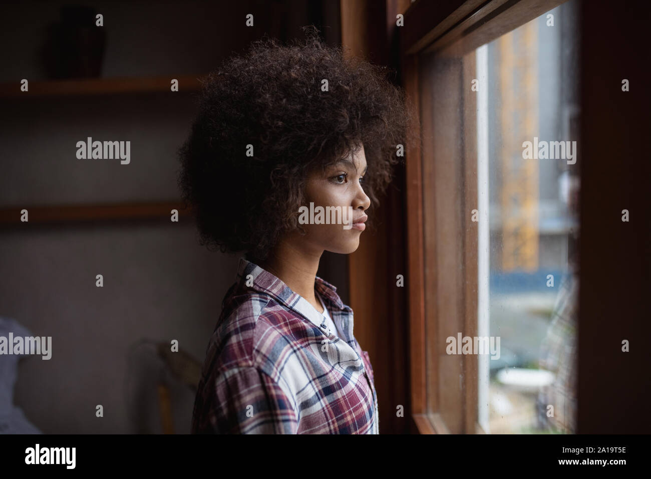 Giovane donna che guarda fuori da una finestra Foto Stock