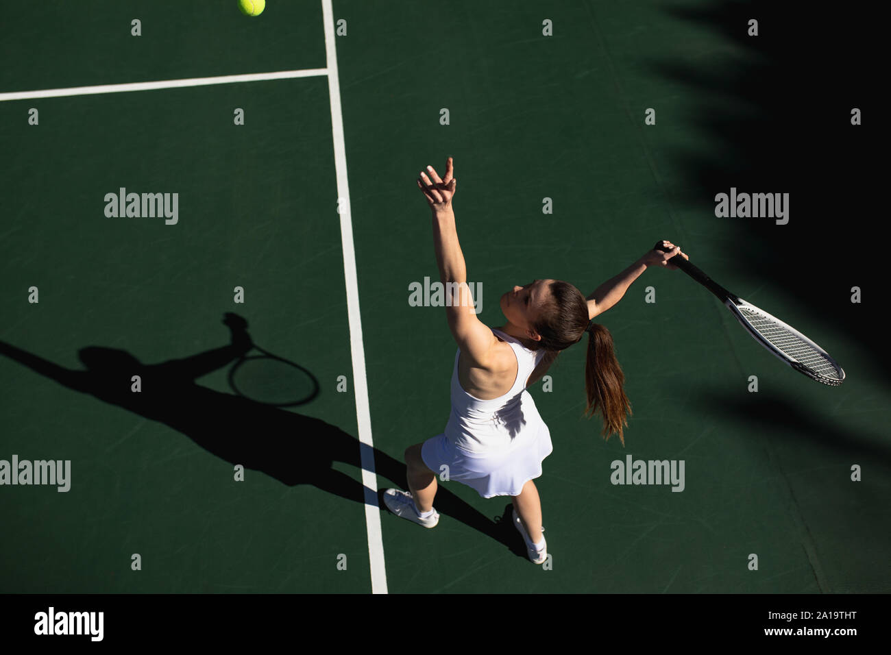 Donna che gioca a tennis in una giornata di sole Foto Stock