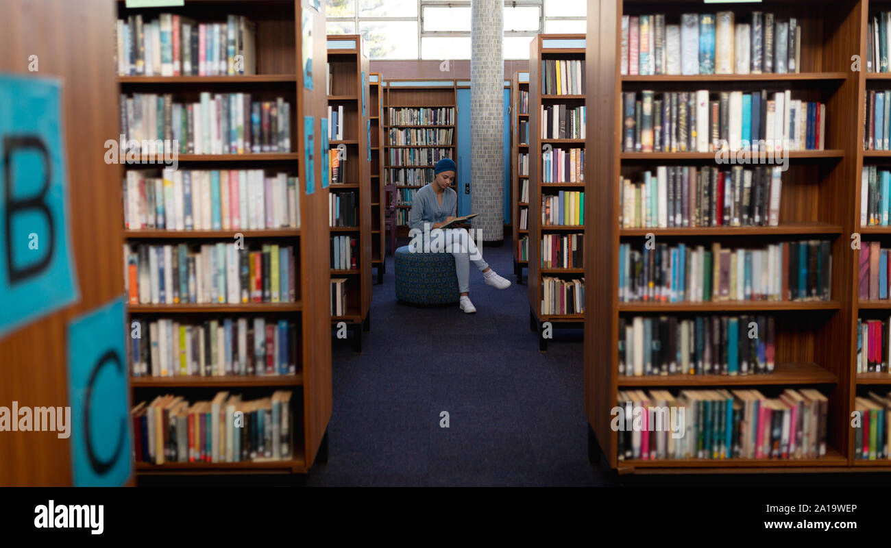 Giovane donna studiare in biblioteca Foto Stock