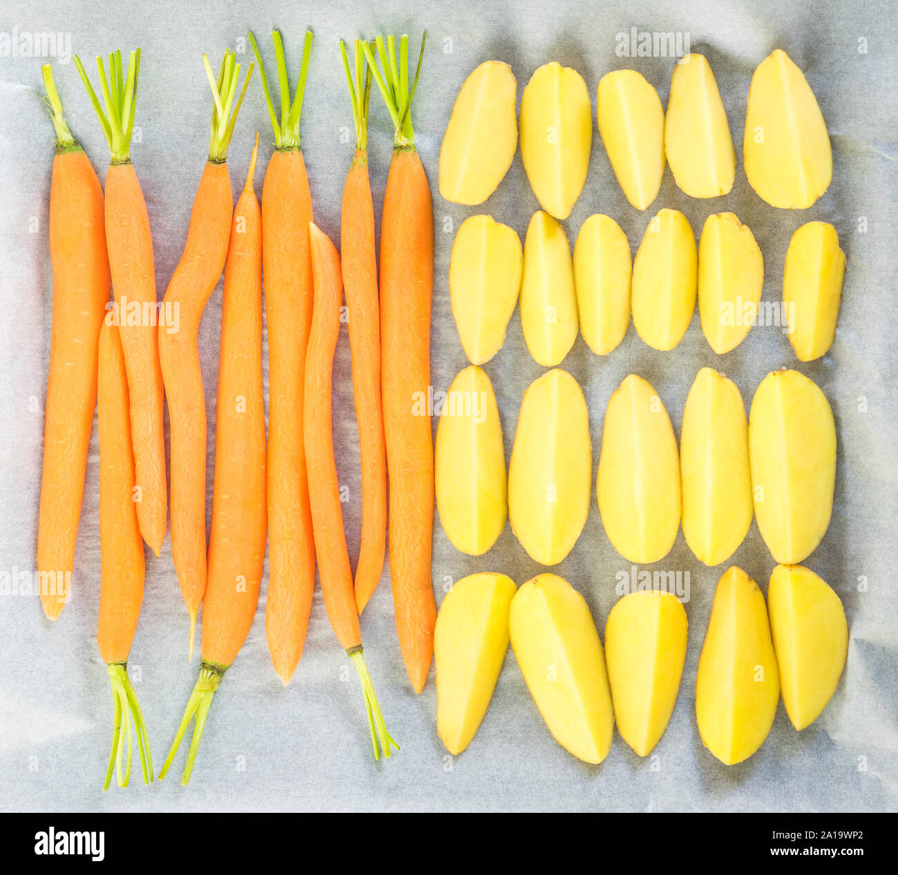 Carote e patate su carta pergamena preparato per la cottura alla griglia in stufa Foto Stock