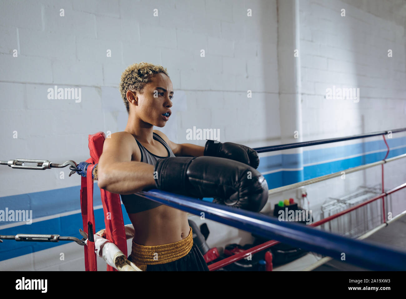 Boxer femmina in appoggio in un angolo del pugilato ring a boxing club Foto Stock