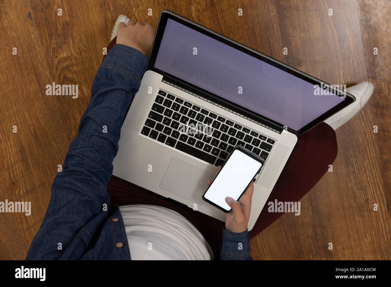 Giovane uomo di casa utilizzando lo smartphone e il computer portatile Foto Stock