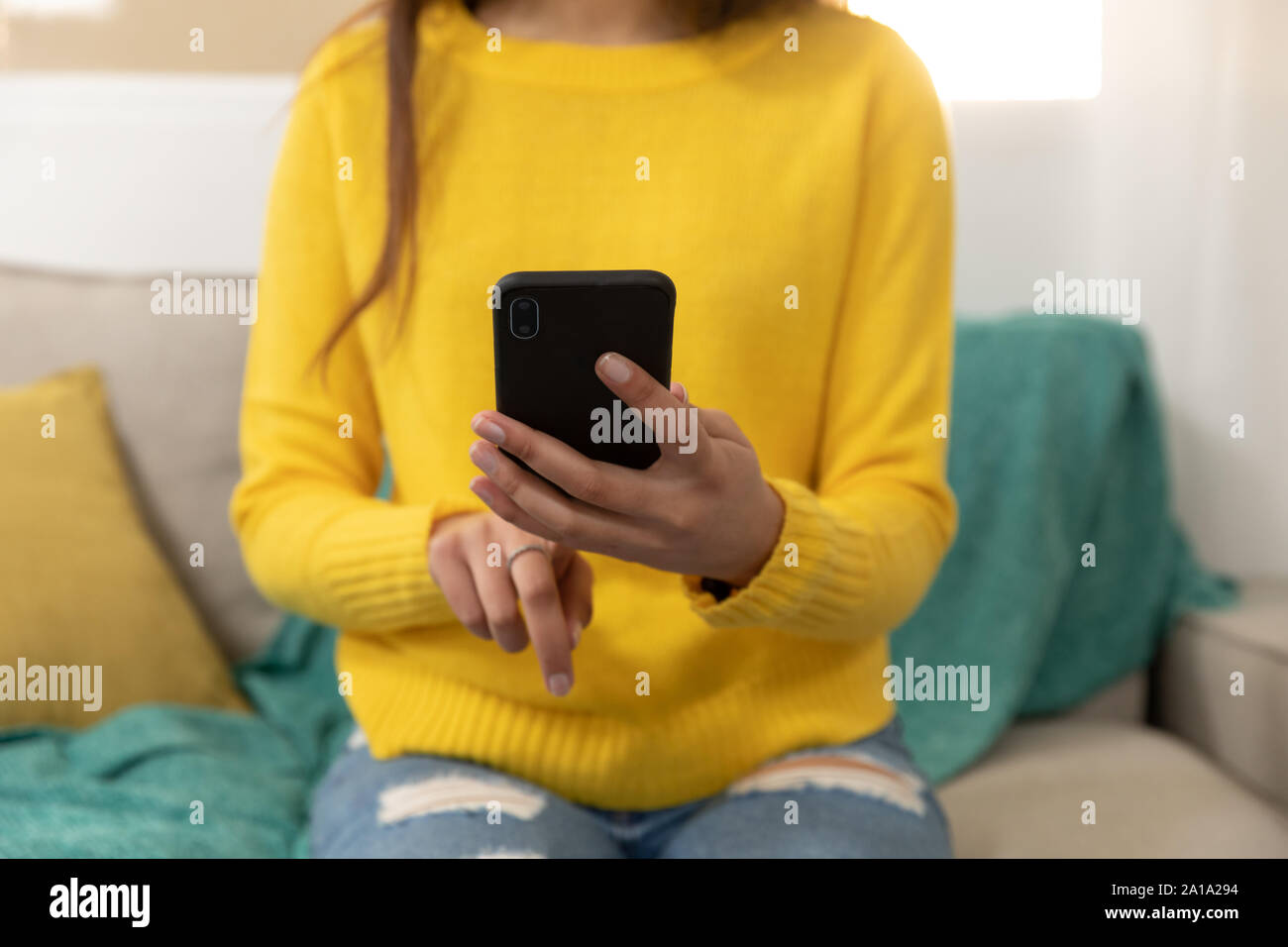Giovane donna di casa utilizzando uno smartphone Foto Stock