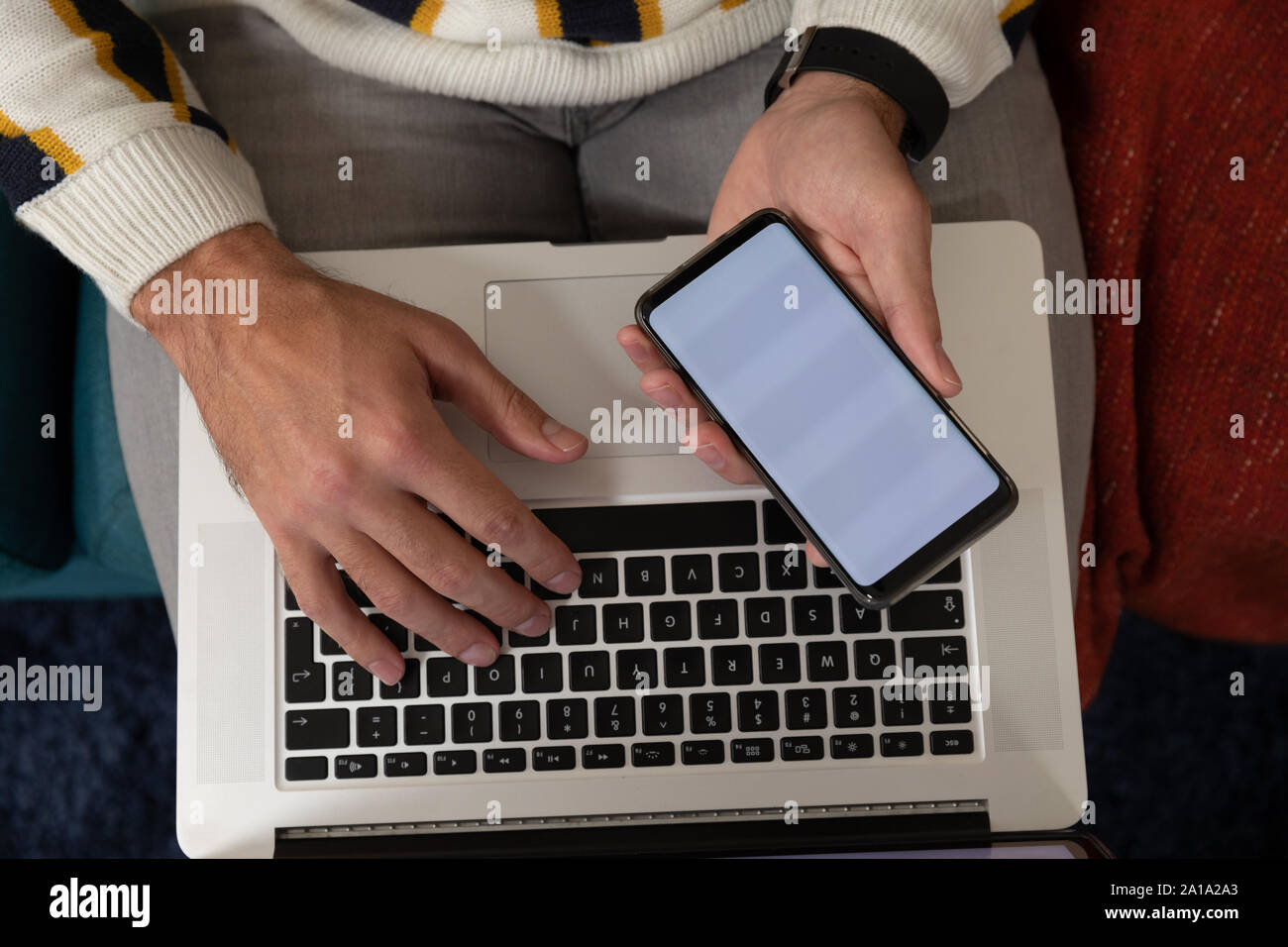 Uomo che utilizza lo smartphone e il computer portatile Foto Stock