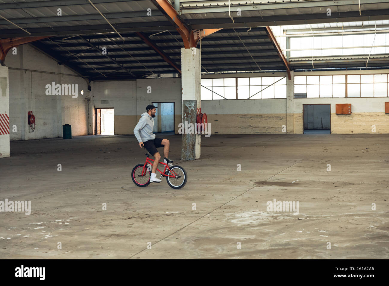 Il pilota di BMX in un magazzino vuoto Foto Stock