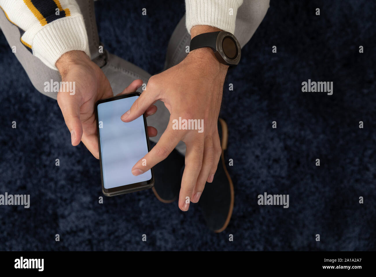 Giovane uomo di casa utilizzando uno smartphone Foto Stock