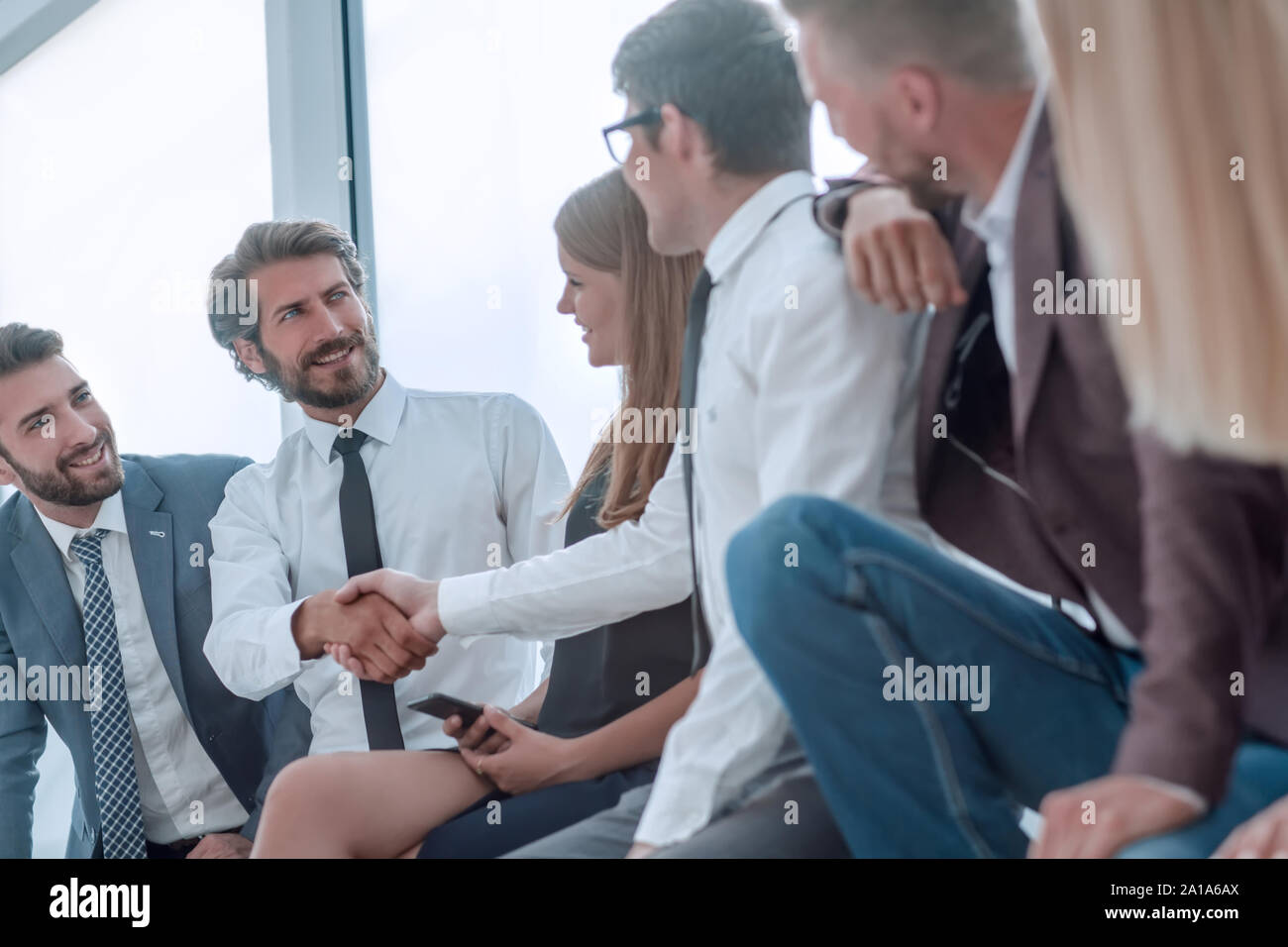 I giovani uomini di affari che stringono le mani mentre è seduto nella lobby di office Foto Stock