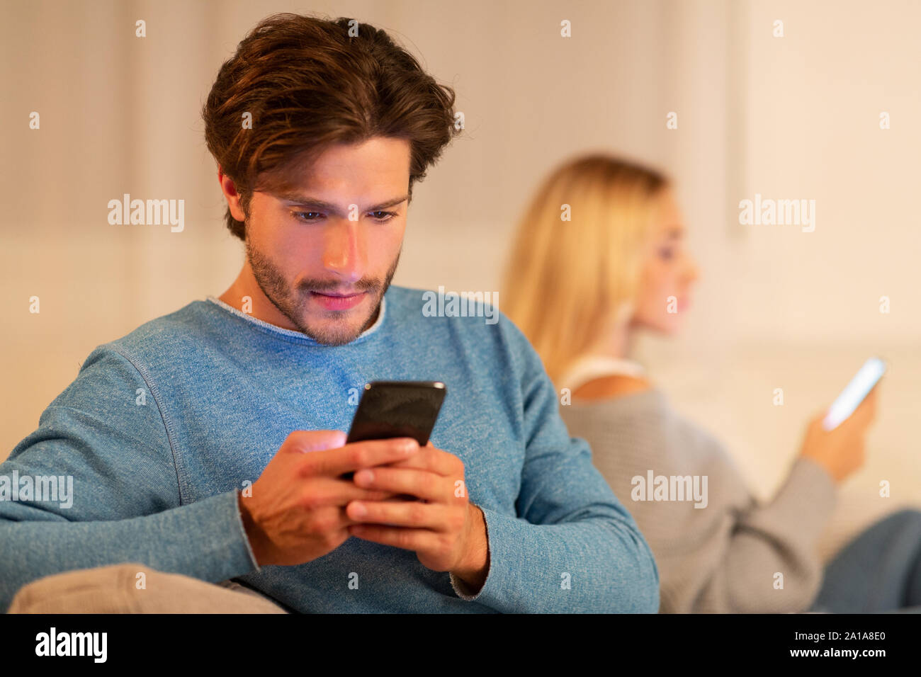 Barare marito a chattare su telefono accanto alla moglie a casa Foto Stock