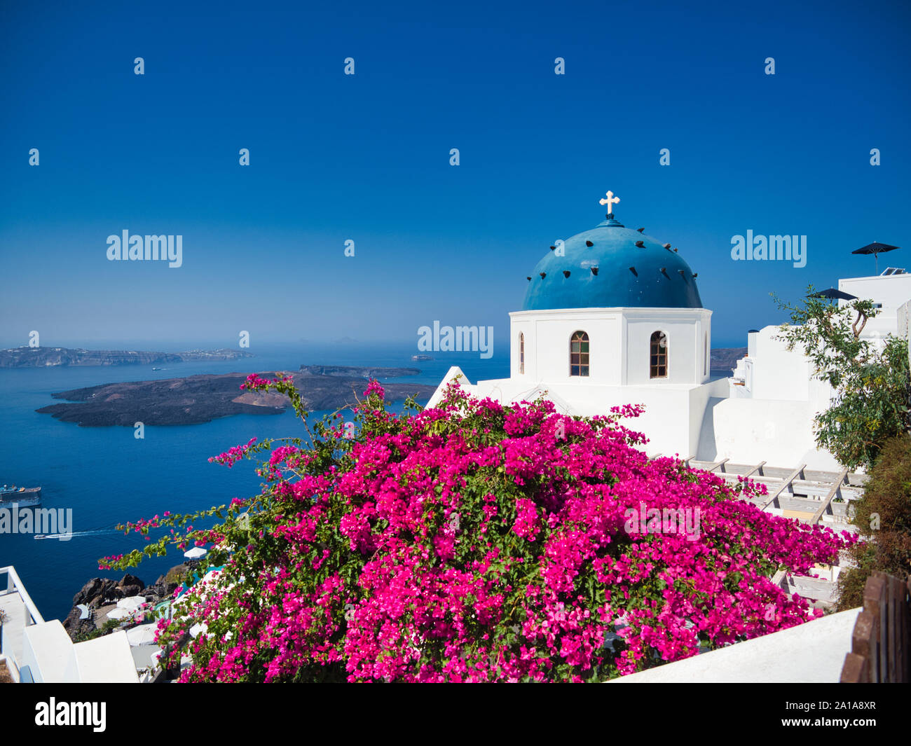 Una vista maestosa di Nikolaus monastero con Chiesa a cupola e fiori di colore rosa sulla riva del mare dell'isola di Santorini in Grecia Foto Stock