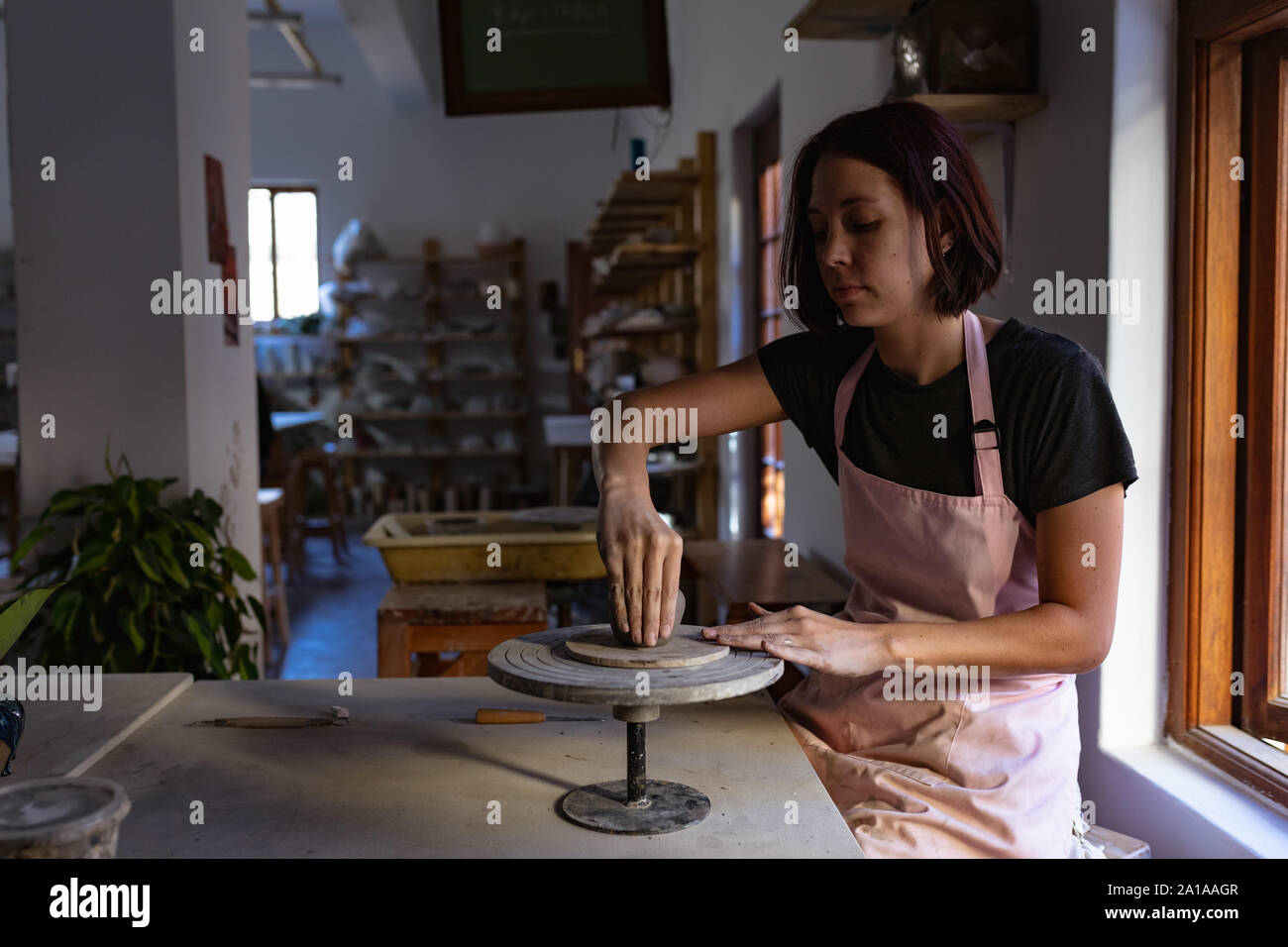 Potter femmina in un studio in ceramica pentola di formatura sulla ruota di fascettatura Foto Stock