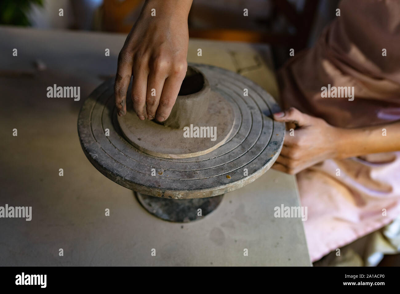 Potter femmina in un studio in ceramica pentola di formatura sulla ruota di fascettatura Foto Stock