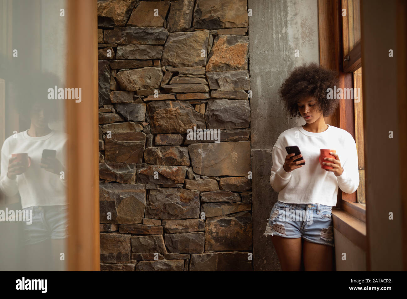 Giovane donna utilizza lo smartphone e di bere il caffè Foto Stock