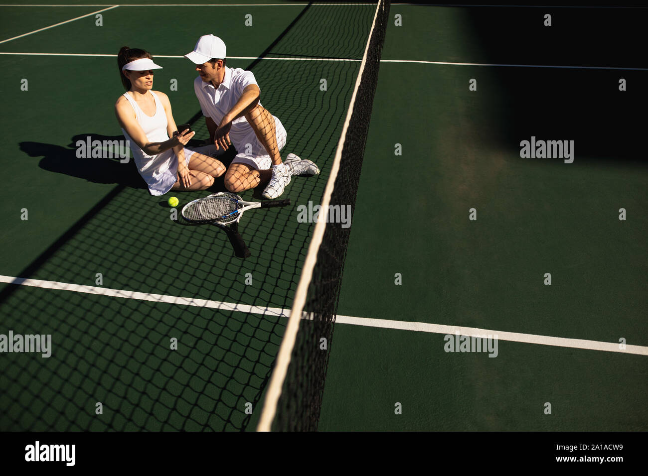 Donna e uomo utilizza lo smartphone al campo da tennis in una giornata di sole Foto Stock