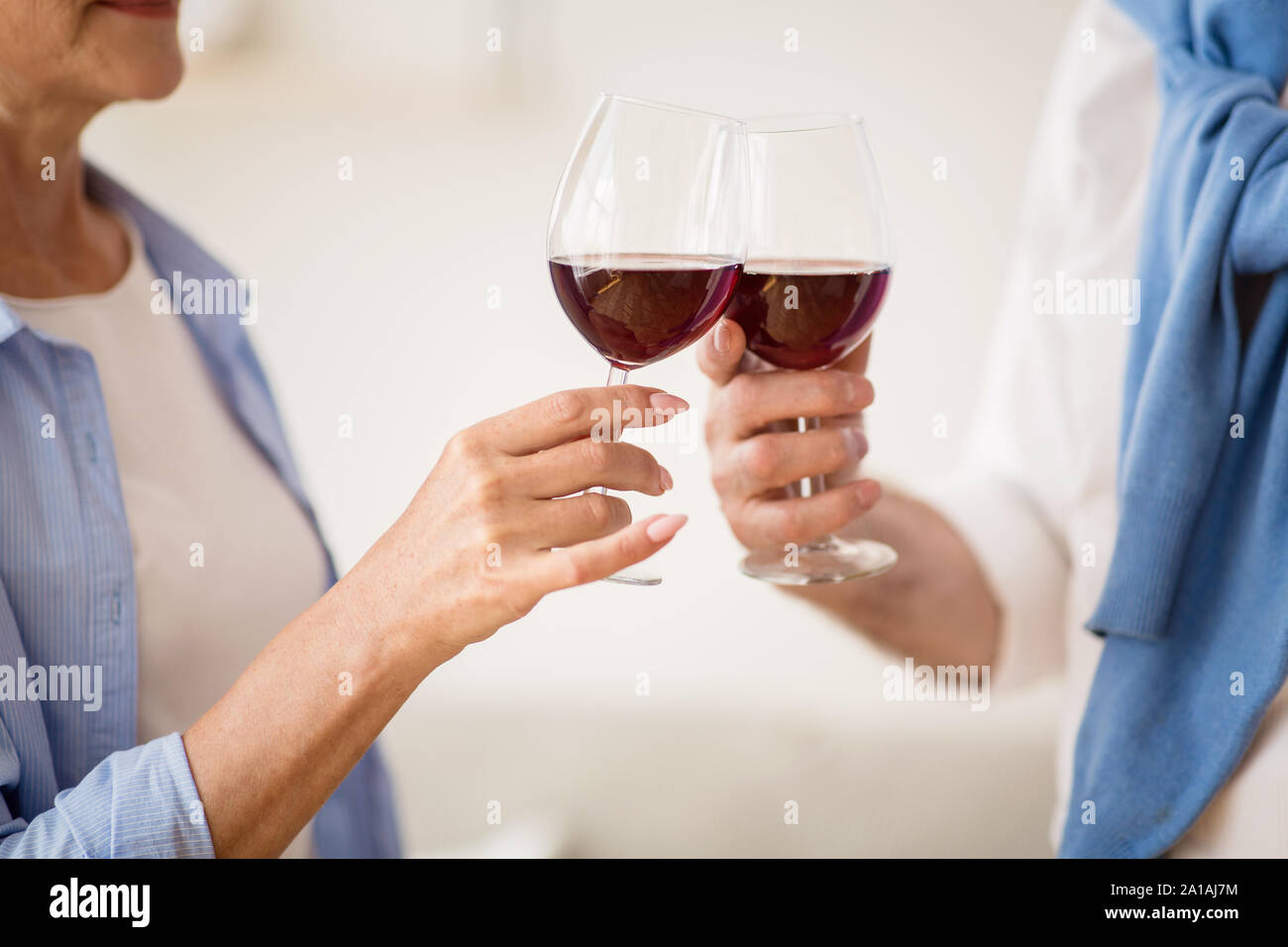 Coppia matura tintinnanti bicchieri da vino rosso a casa Foto Stock