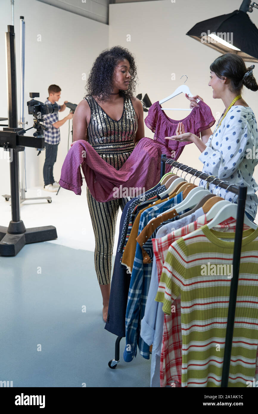 La stilista scegliendo i vestiti per la moda da indossare su foto riprese in studio Foto Stock