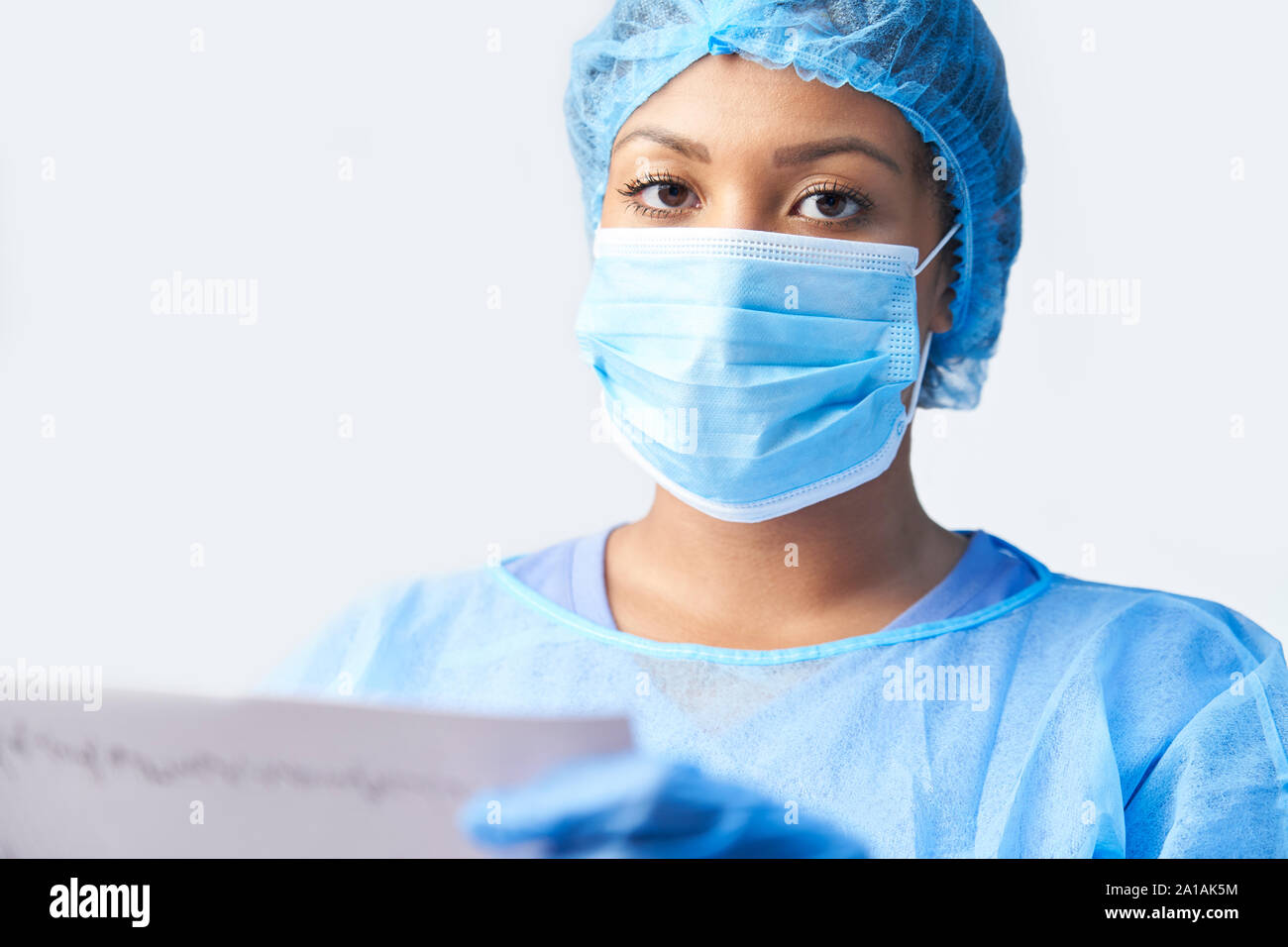 Studio ritratto di donna chirurgo indossando camice e maschera Holding Medical Stampare Foto Stock