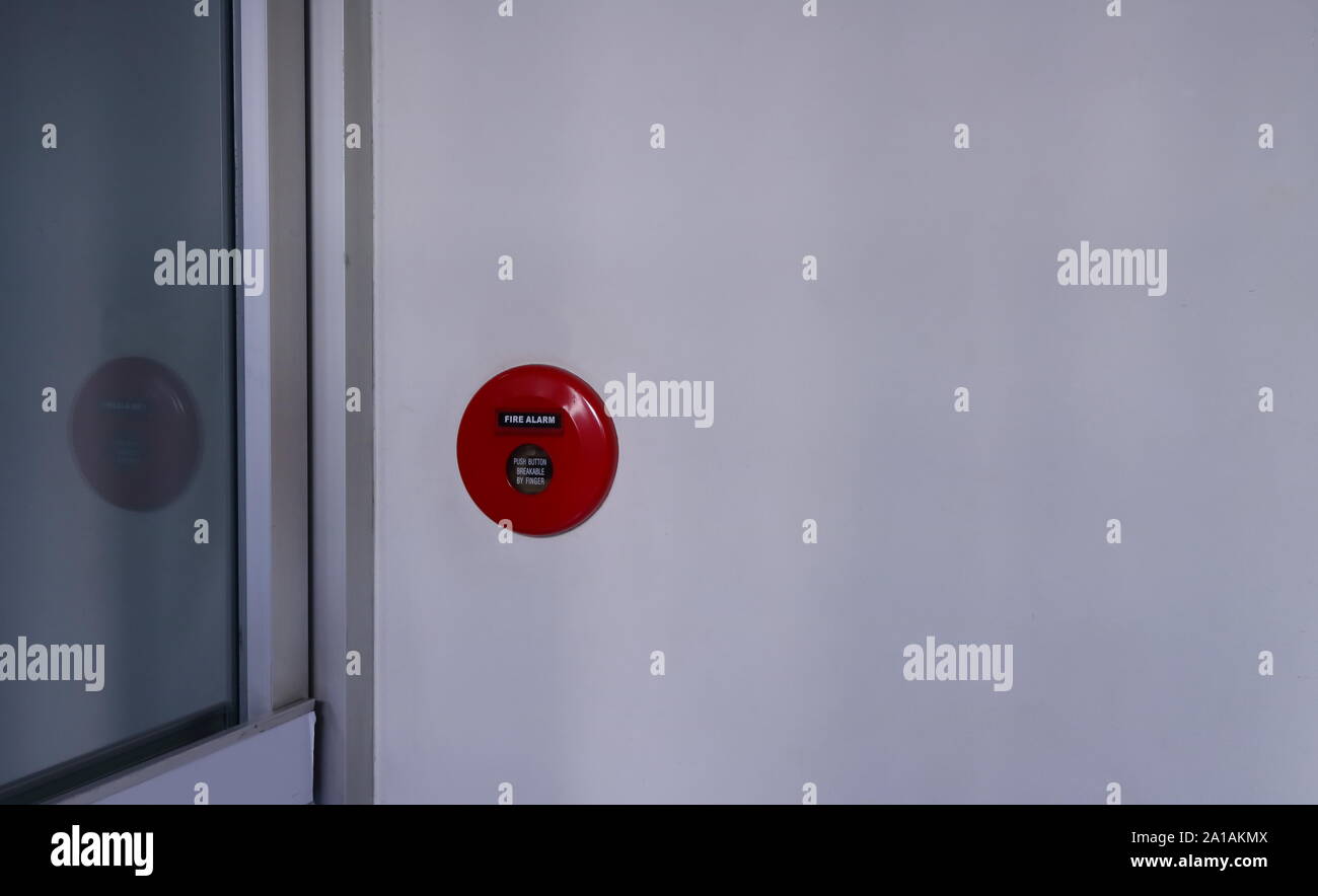 Closeup manuale stazione di spinta del sistema di allarme antincendio, installato sulla parete vicino alla porta di vetro di un edificio, il concetto di sicurezza Foto Stock