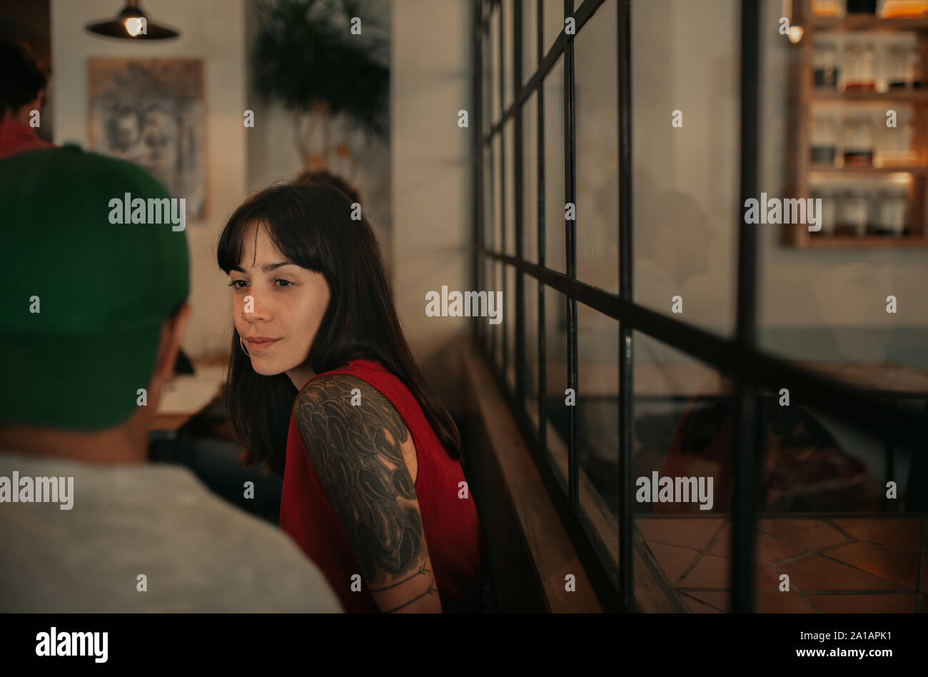 Giovane donna con tatuaggi a parlare con gli amici in un bar Foto Stock