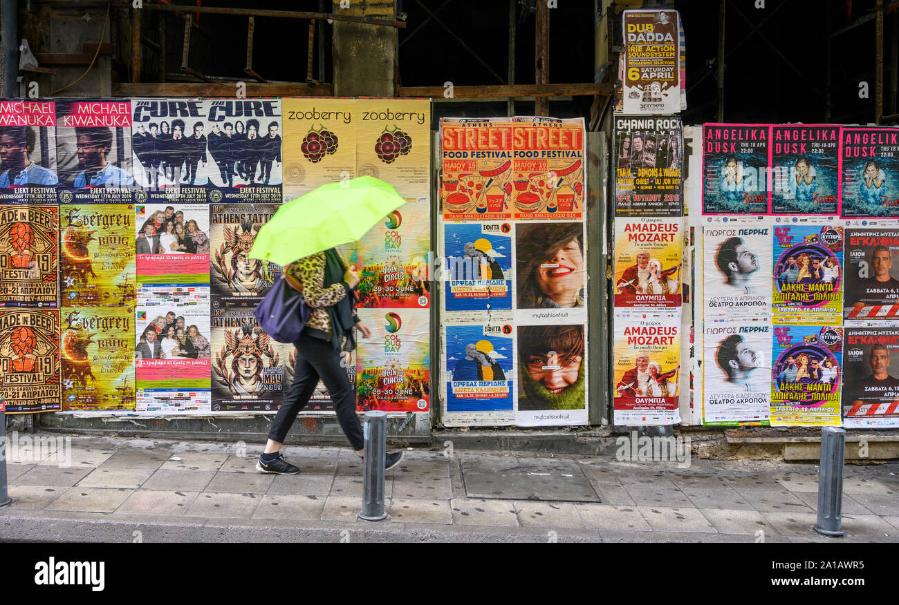 Una donna cammina davanti ad una parete del poster di intrattenimento nel centro di Atene, Grecia Foto Stock