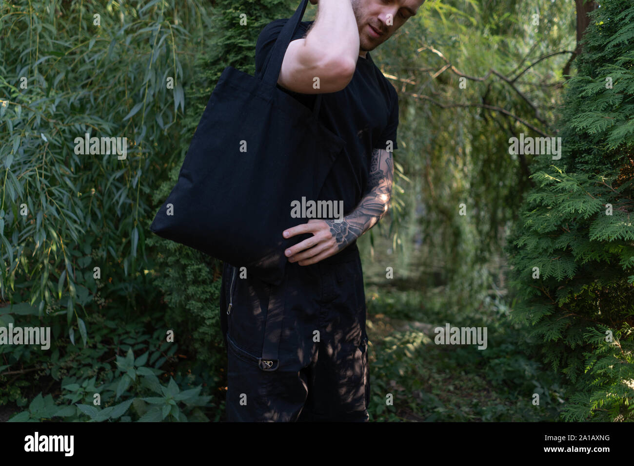 Close up uomo in moda casual sportivo usura con nero borsa vuota all'aperto in autunno o d'estate il parco. Luogo per lo spazio vuoto. Copia dello spazio. Eco amico Foto Stock