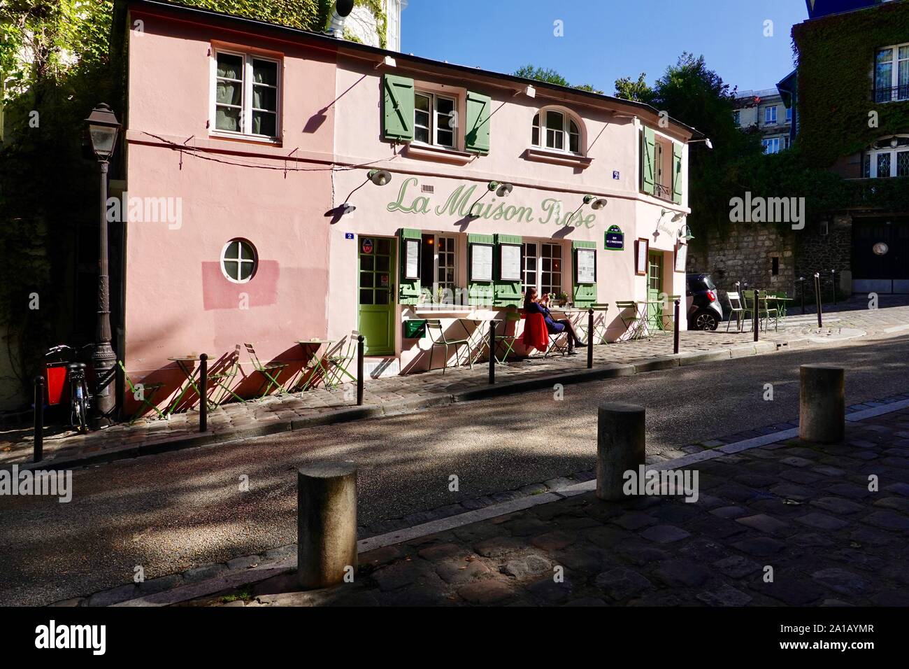 Donna seduta sulla terrazza, al sole, fuori la Maison Rose café, Montmartre, Parigi, Francia. Foto Stock