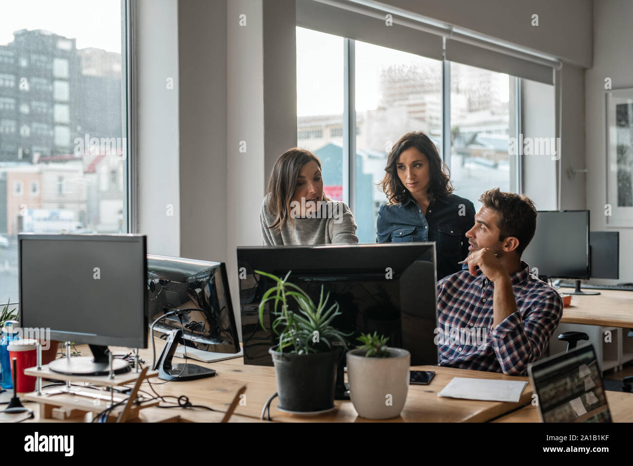 Diversi gruppi di giovani progettisti che lavorano su un computer insieme Foto Stock