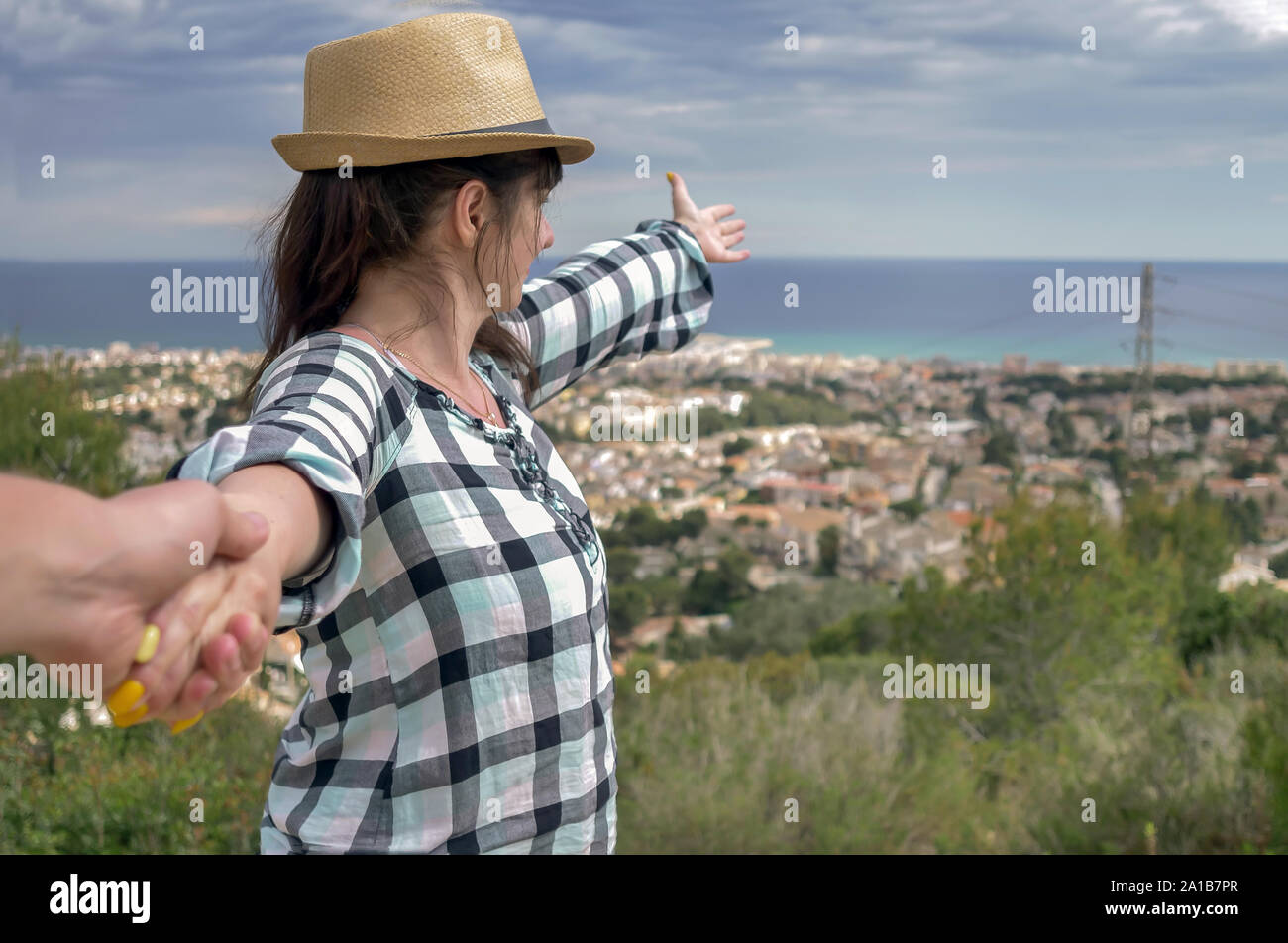 Una bruna ragazza conduce un ragazzo dalla mano mostrerà la città di fronte a loro. Follow me il concetto di attività ricreative e del turismo Foto Stock