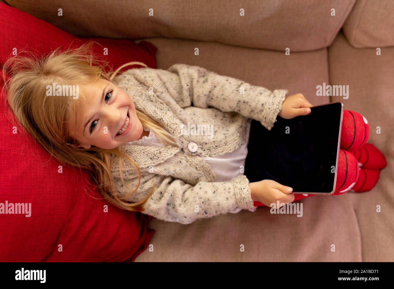 Ragazza seduta a casa con il computer tablet Foto Stock