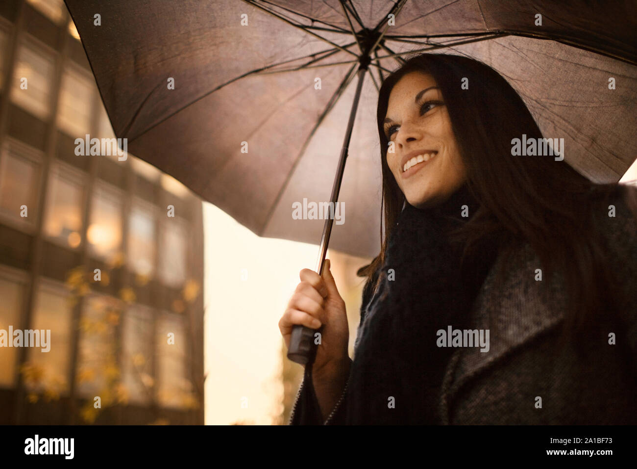 Sorridente ragazza camminare a lavorare in un giorno di pioggia. Foto Stock