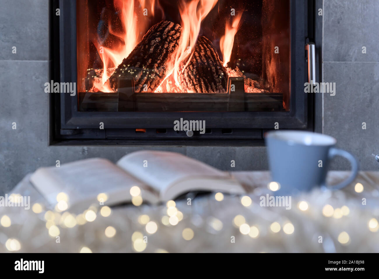 Concetto di Hygge con libro aperto e la tazza di tè vicino al caminetto Foto Stock