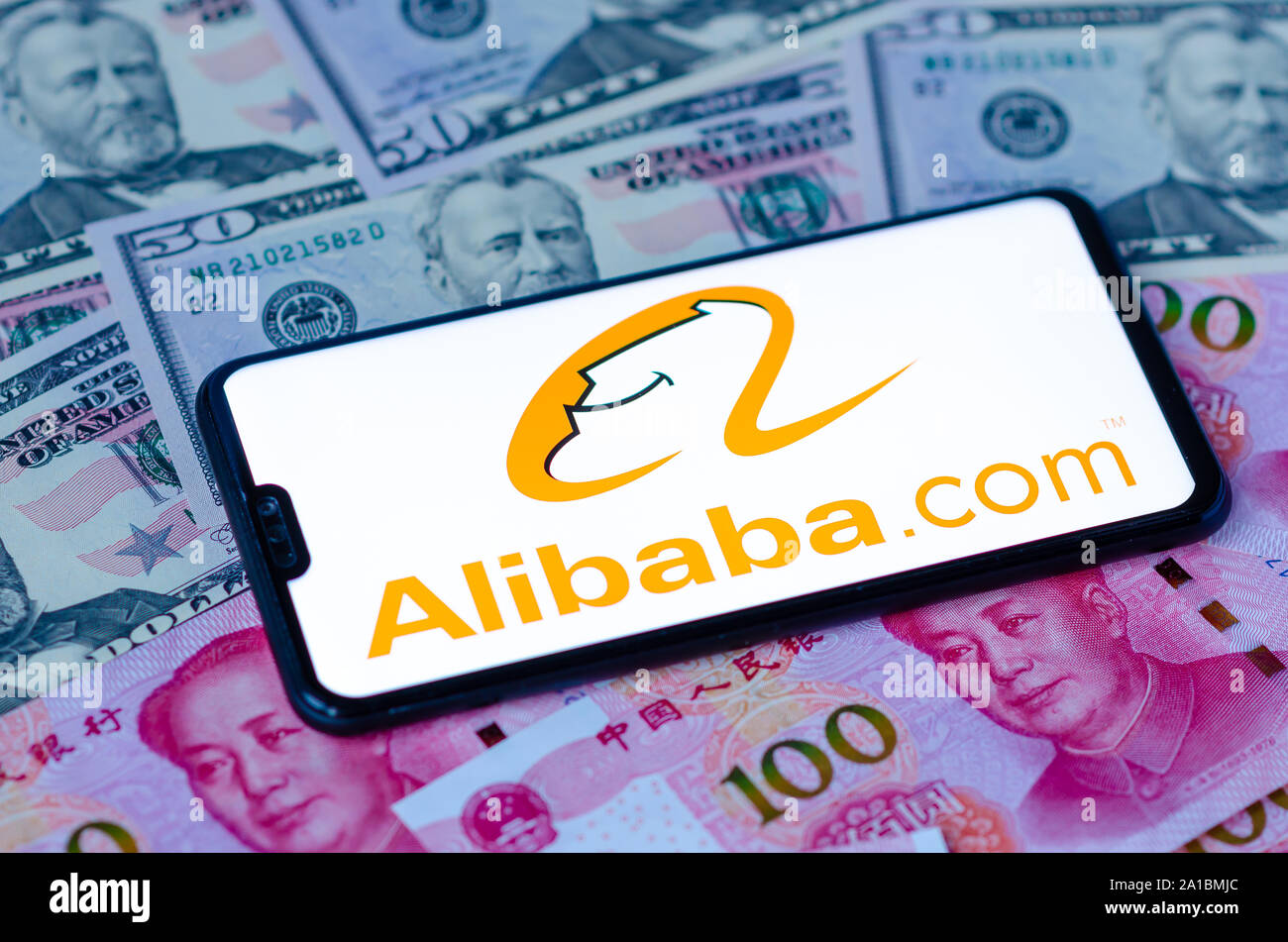 Alibaba com logo sullo schermo dello smartphone, posto sul dollaro e yuan cinese di banconote. Concetto per international retail company Alibaba Foto Stock