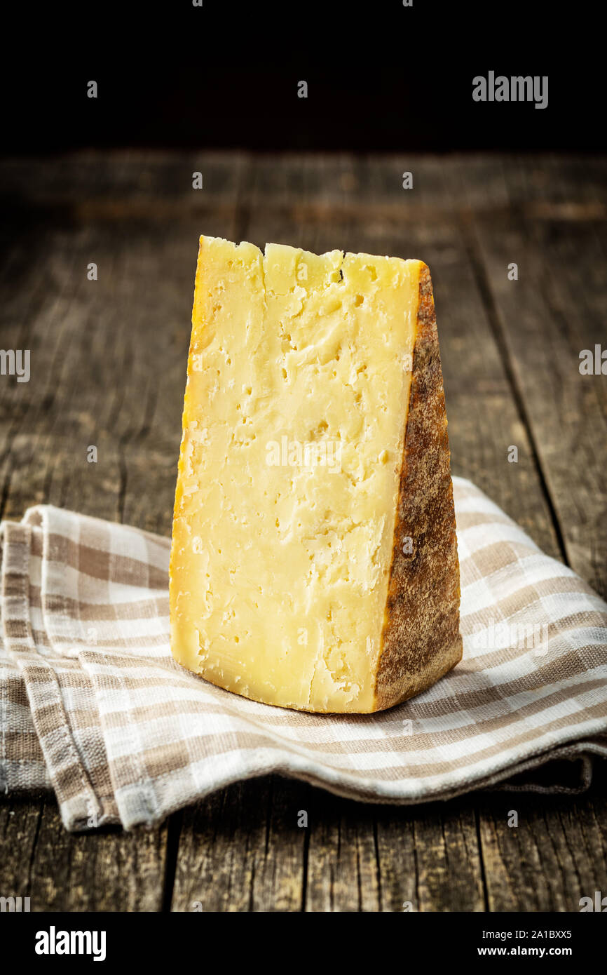 Blocco del gustoso formaggio sul vecchio tavolo in legno. Foto Stock