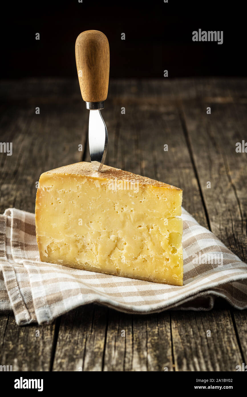 Blocco del gustoso formaggio sul vecchio tavolo in legno. Foto Stock