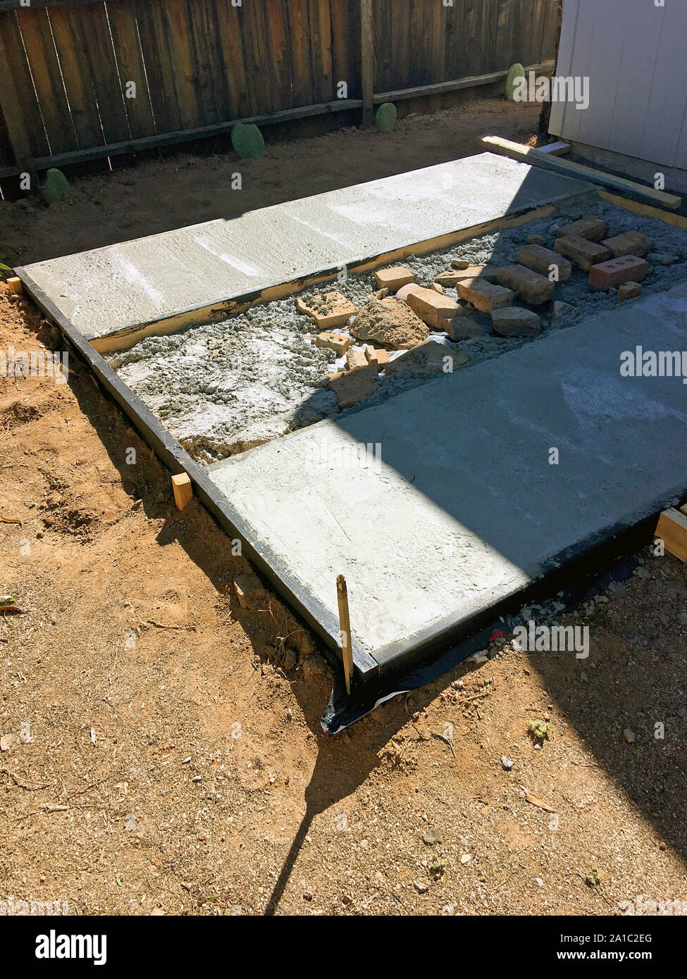 Essiccazione di cemento dopo essere stata versata in un asfalto quadro in legno per una base rialzata per un capannone Foto Stock