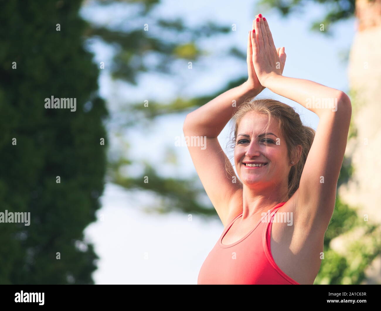 Donna nella sua Anni Trenta facendo Yoga nel parco in un giorno di estate Foto Stock