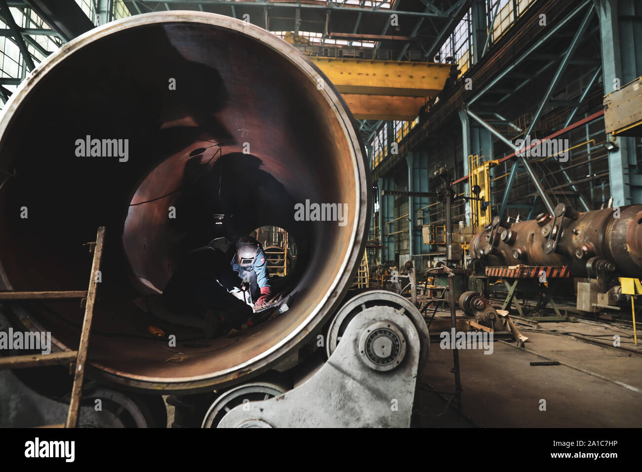 Donna saldatrice in una sporca e vecchia ma ancora funzionante di opere in metallo, vecchio stile, factory Foto Stock