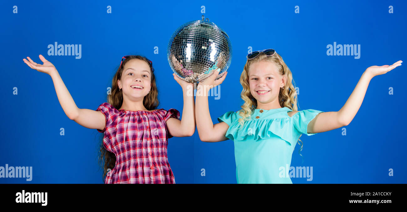 Concetto di intrattenimento. Sorelle amici con palla da discoteca. Iniziare a parte. Allegro kids tenere palla da discoteca. Discoteca danze. Musica retrò. Gli specchi riflettenti discoteca luci di atmosfera. Holiday celebrazione. Foto Stock