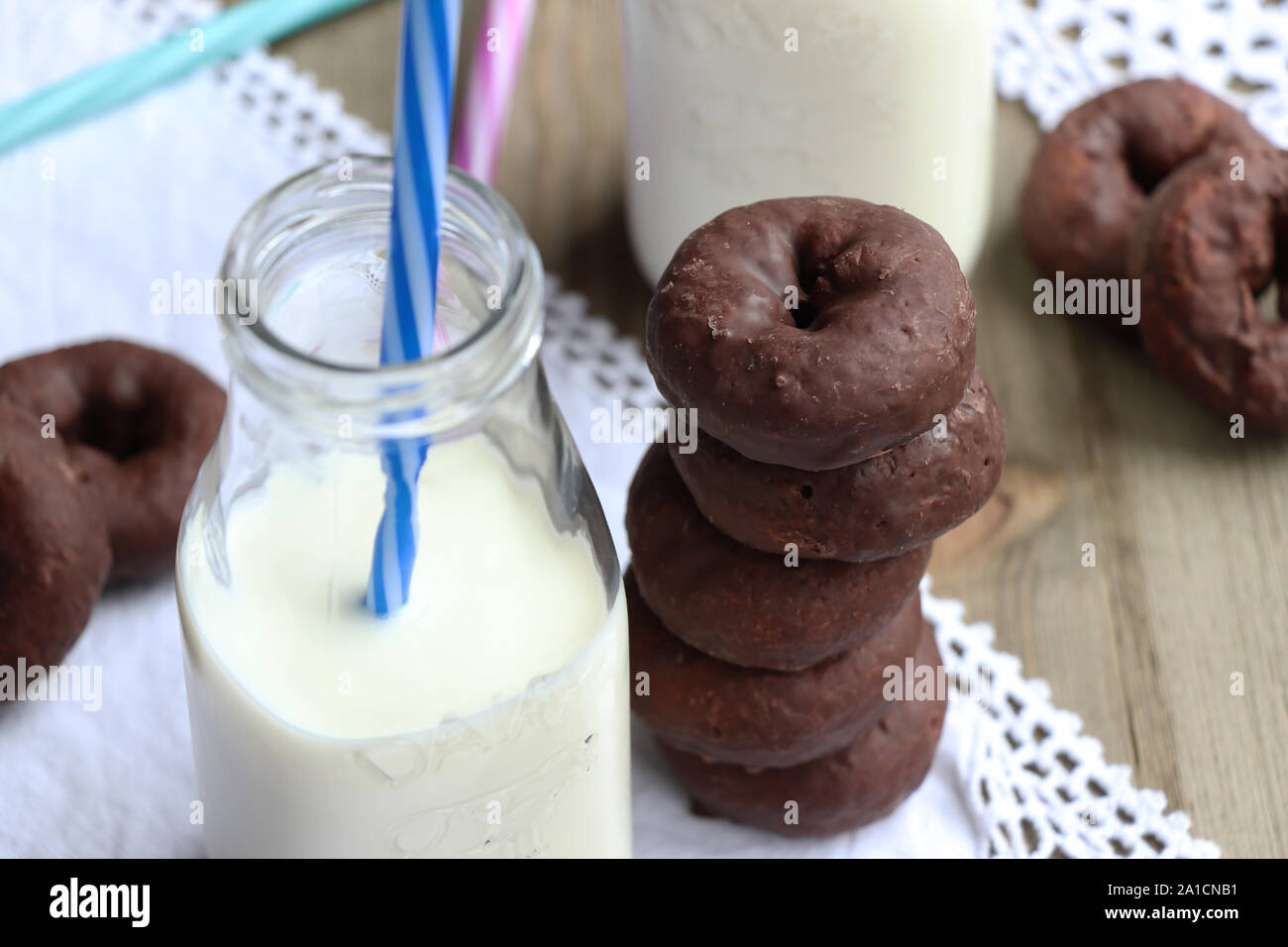 Una pila di ciambelle di cioccolato e un bicchiere di latte fresco Foto Stock