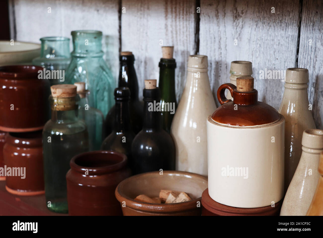 Una mensola con diverse bottiglie di vetro, tazze in ceramica, e ciotole a Fort Nisqually a Tacoma, Washington Foto Stock
