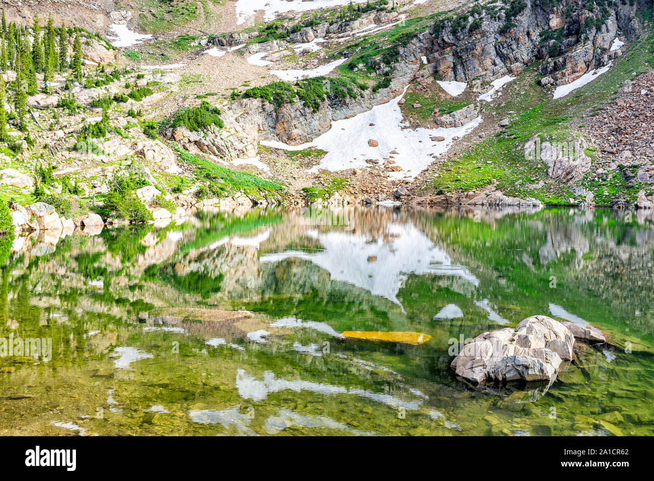 Albion bacino, Utah estate con closeup riflessione di acqua sul lago Cecret in montagne Wasatch con rocce, neve e dal colore verde Foto Stock
