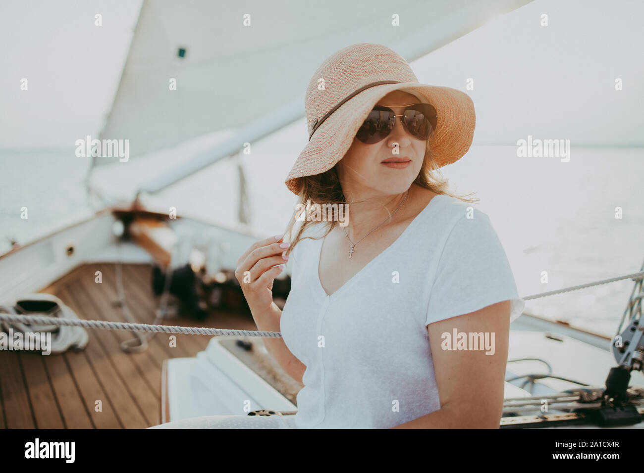 Metà di età donna che indossa cappello per il sole in barca a vela Foto  stock - Alamy