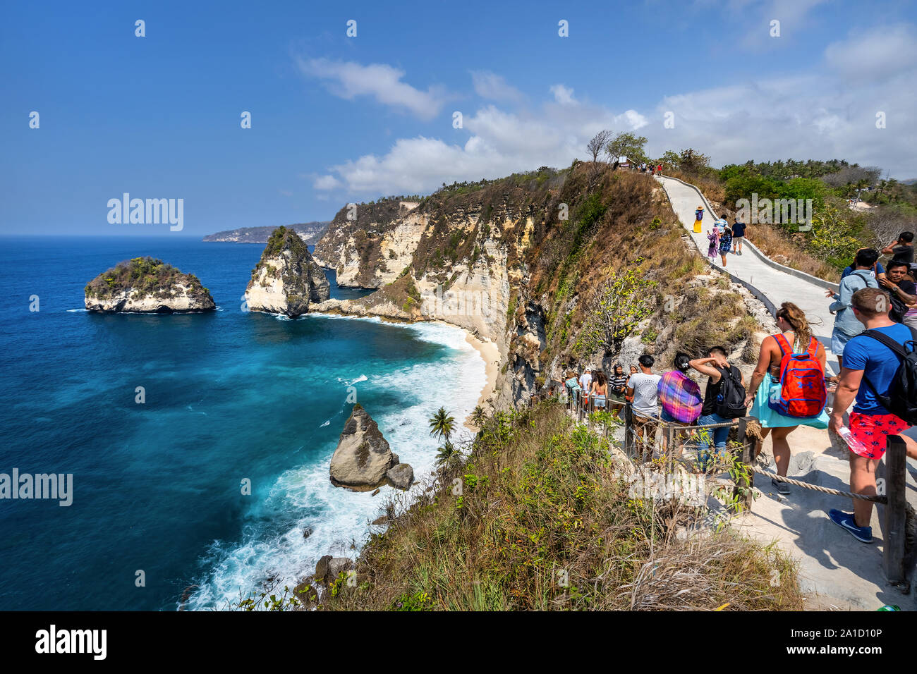 Vista aerea del popolo di viaggio con zaino e in pantaloncini corti sull'oceano, scogliere e spiaggia tropicale sfondo. Atuh beach, Nusa Penida, Indonesia. Foto Stock
