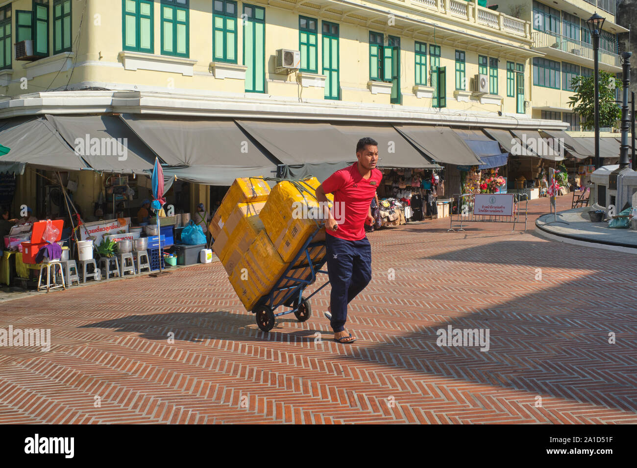 Un portiere Myanmarese tira il suo carrello carico di merci attraverso Saphan Han, una piccola klong (canale) ponte in Pahurat / area di Chinatown, Bangkok, Thailandia Foto Stock