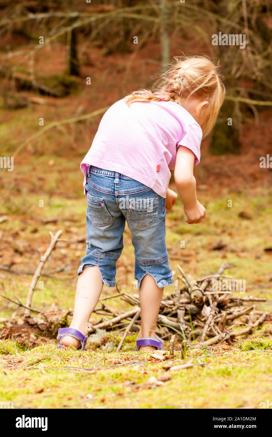 Bambina da solo la ricerca di legno e il cibo nella foresta. Foto Stock