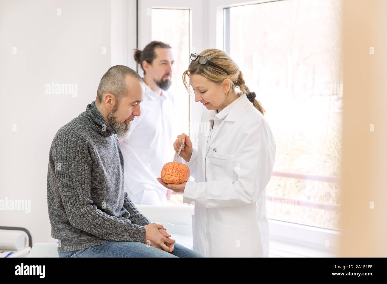 Neurologo femmina è che mostra un paziente di sesso maschile qualcosa su un cervello sintetico Foto Stock