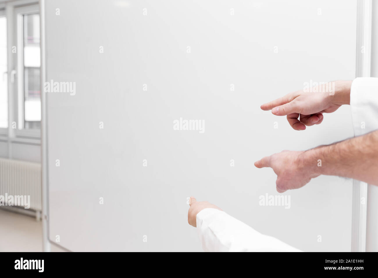 Tre mani puntando ad una lavagna vuota con copyspace Foto Stock