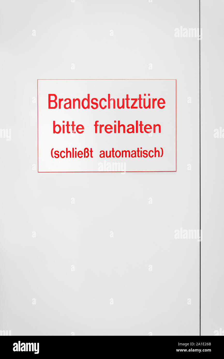 Segno rosso con lettere colorate su una porta bianca, con parole tedesche che significa incendio porta di emergenza Foto Stock