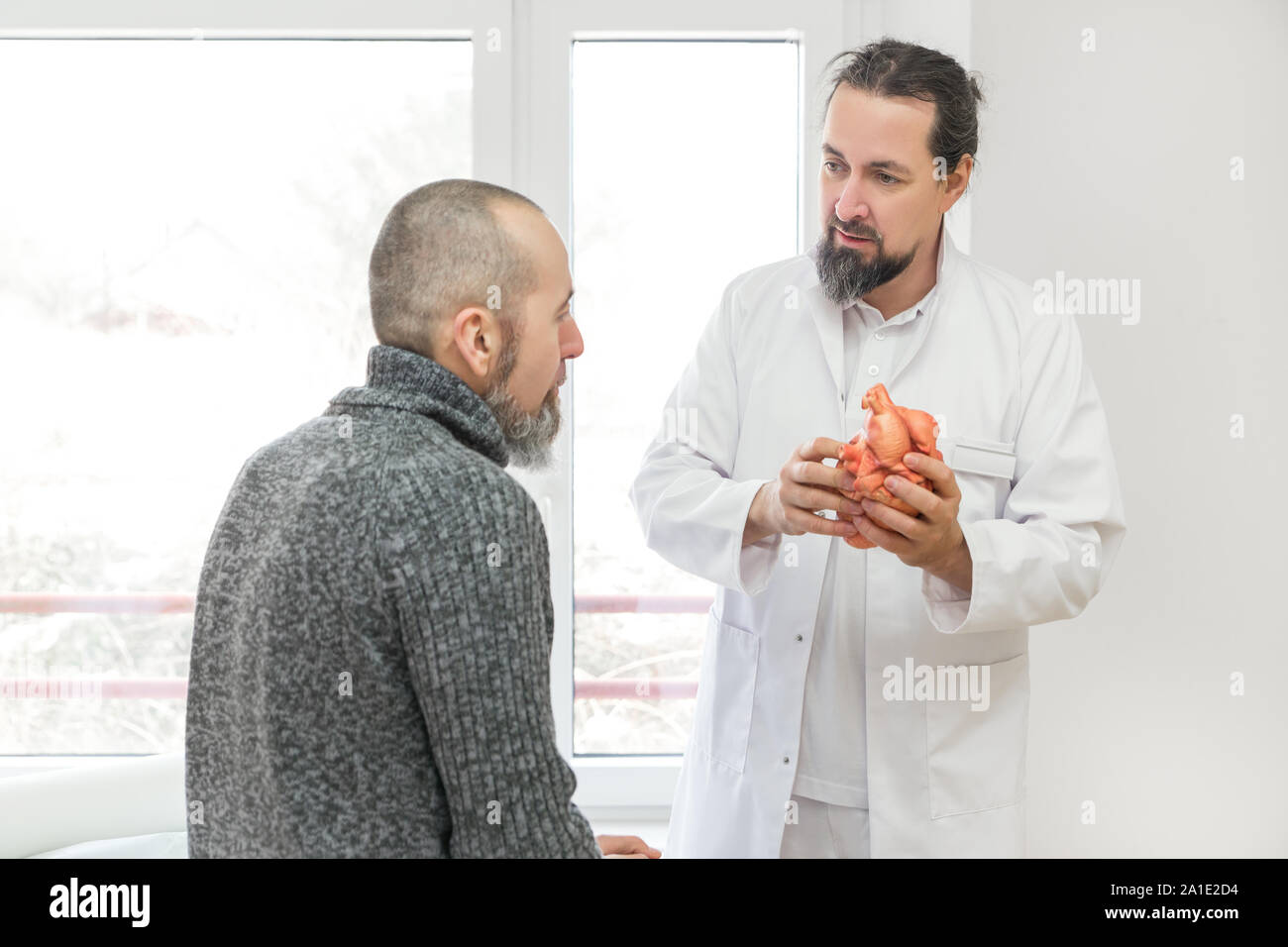 Cardiologo maschio o medico è che mostra un paziente di sesso maschile di un cuore sintetico, dando una spiegazione o una consultazione Foto Stock